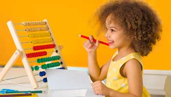 A preschool girl sitting at an abacus getting ready to learn math.