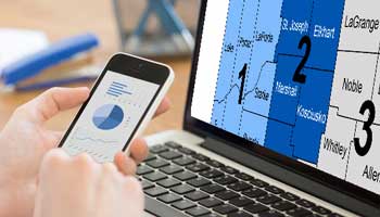  A person viewing map data on computer screen and pie chart on phone.